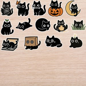 May include: A collection of black cat stickers in various poses. Some cats are depicted with a butterfly, a fish skeleton, and a pumpkin. Other cats are shown with a ball of yarn, a laptop, and a paper bag. The stickers are on a wooden surface.