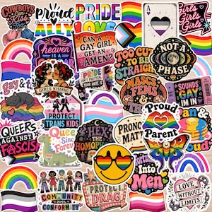 May include: A collection of colorful LGBTQ+ pride stickers with various designs and text. The stickers feature rainbows, hearts, flags, and phrases like "Proud," "Love," and "Protect Trans Kids." The stickers are on a light wood-grain surface.