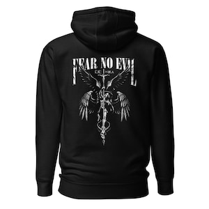 May include: Black hooded sweatshirt with a white graphic on the back. The graphic features an angel with outstretched wings, a skull, and the text "FEAR NO EVIL". The brand name "NIKA" is also visible.