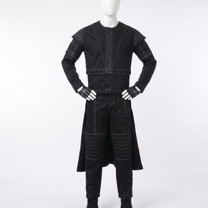 May include: A black long-sleeved jacket and matching trousers set featuring prominent white contrast stitching. The jacket has structured shoulders and a high neckline. The trousers include knee detailing and a side pocket. Black gloves and boots complete the outfit.