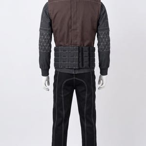 May include: A black and brown tactical outfit on a mannequin. The outfit features a brown vest with white stitching, a black jacket with geometric patterns on the sleeves, and black trousers with white stitching. The outfit is designed for protection and utility.