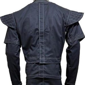 Pu&ograve; includere: Una giacca blu navy scuro con spalline strutturate con cuciture bianche orizzontali, maniche lunghe e una cucitura centrale verticale. Il capo presenta una silhouette squadrata con pannelli rinforzati e impunture bianche a vista.