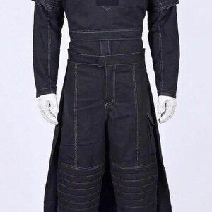 May include: A black long-sleeved tunic and matching trousers set featuring white contrast stitching. The top has a structured shoulder design and a central chest panel. The trousers include a wide waistband, side panels, and quilted knee sections.