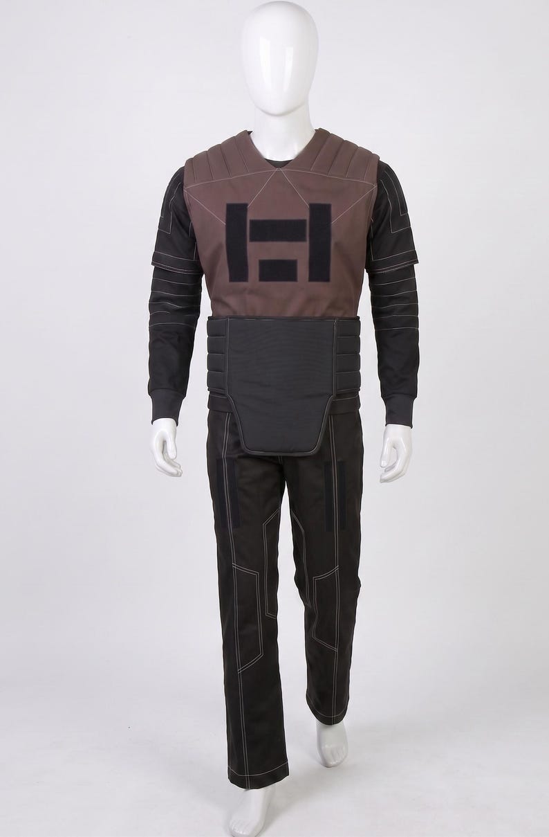 May include: A full-body costume displayed on a mannequin. The costume includes a brown vest with a black geometric design, a black long-sleeved shirt, black trousers, and a black belt. White stitching accents the seams.