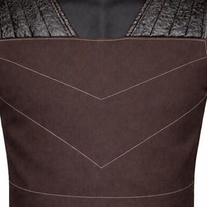 May include: A dark brown vest featuring a smooth matte finish on the main body with contrasting black textured shoulder panels. The garment includes prominent white topstitching that forms a large chevron pattern across the chest area.