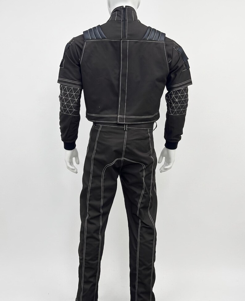 May include: A black two-piece outfit consisting of a high-neck jacket and matching trousers. The jacket features shoulder padding, long sleeves with a white geometric grid pattern on the forearms, and white contrast stitching throughout.