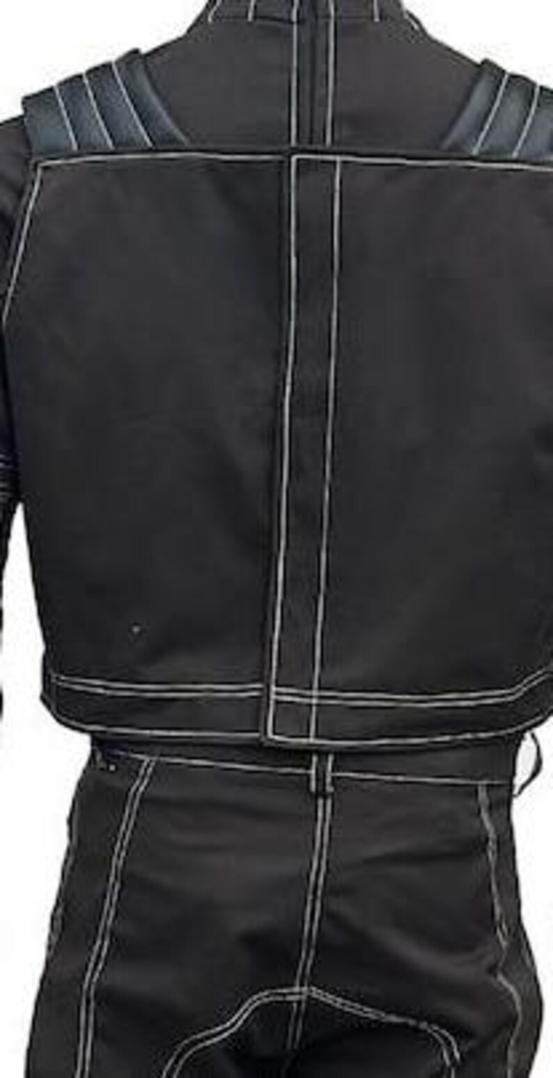 May include: A black jacket and matching trousers set featuring prominent white contrast stitching throughout. The jacket includes a high collar, a vertical center seam, and padded shoulder detailing. The trousers feature a structured fit.