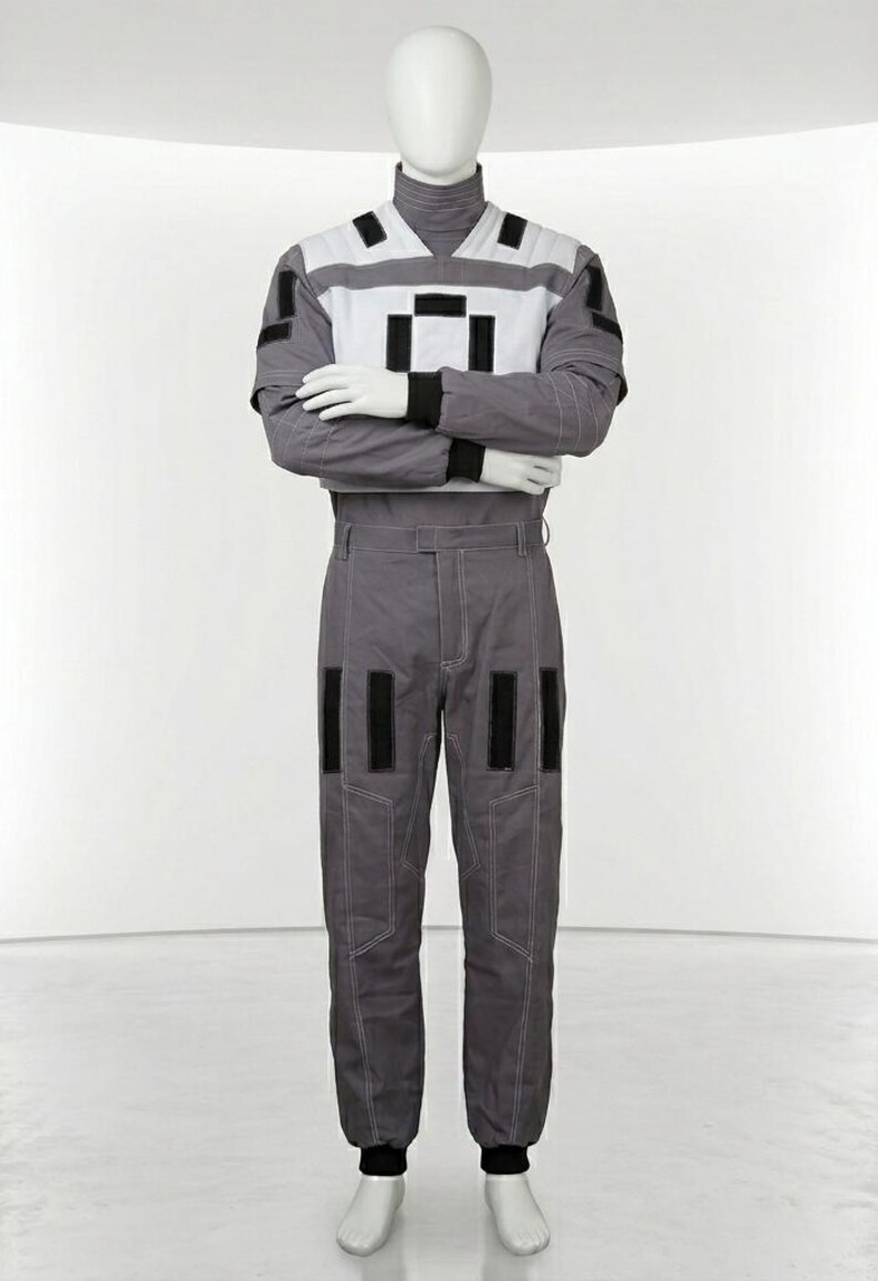 May include: A gray and white jumpsuit featuring a high collar, long sleeves with black cuffs, and a white chest panel with black rectangular accents. The pants include matching gray fabric with white contrast stitching and black rectangular patches.