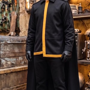 May include: A black long-sleeved jacket with a prominent vertical yellow stripe down the front, paired with black trousers, black gloves, and black shoes. The jacket features a structured collar and a matching black cape that extends to the floor.