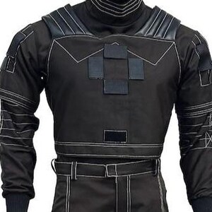 May include: A black tactical long-sleeve shirt featuring a high collar, reinforced shoulder panels, and multiple rectangular hook-and-loop patches on the chest. The garment includes white contrast stitching throughout and matching black trousers.