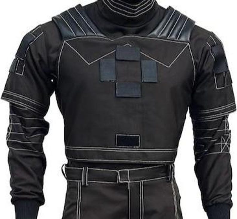 May include: A black tactical long-sleeve shirt featuring a high collar, reinforced shoulder panels, and multiple rectangular hook-and-loop patches on the chest. The garment includes white contrast stitching throughout and matching black trousers.