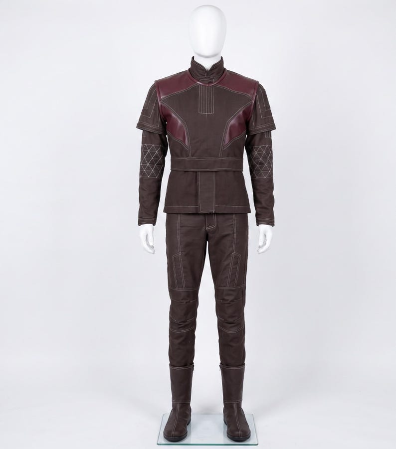 May include: A dark brown long-sleeved jacket and matching trousers set featuring a high collar, burgundy shoulder panels, and white contrast stitching. The sleeves include a geometric quilted pattern, and the jacket has a structured waist belt.
