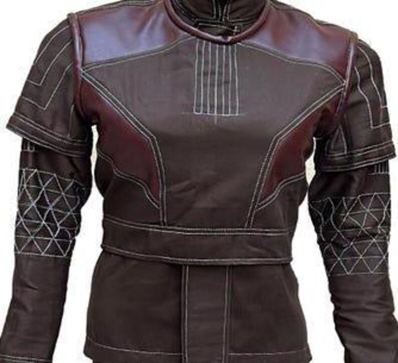 May include: A dark brown jacket featuring maroon shoulder panels, a high collar, and white topstitching. The sleeves display a geometric triangular pattern in white thread, while the bodice includes a horizontal waistband and vertical stitching.