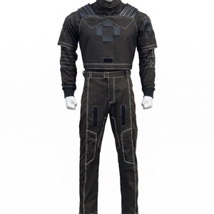 May include: A dark brown tactical-style uniform set consisting of a long-sleeved top with a high collar, shoulder padding, and a central chest patch, paired with matching trousers featuring white contrast stitching and rectangular black accents.