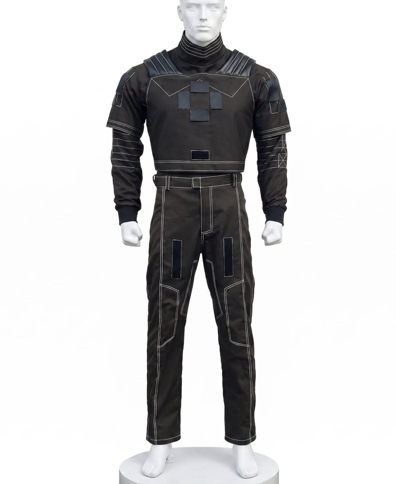 May include: A dark brown tactical-style uniform set consisting of a long-sleeved top with a high collar, shoulder padding, and a central chest patch, paired with matching trousers featuring white contrast stitching and rectangular black accents.