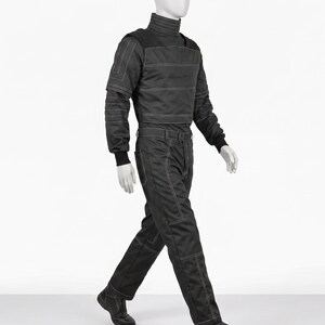 Pu&ograve; includere: Tuta nera con dettagli di cuciture bianche, esposta su un manichino. L'outfit presenta un collo alto, maniche lunghe e una cintura. I pantaloni hanno un design a gamba dritta e il manichino indossa stivali neri.