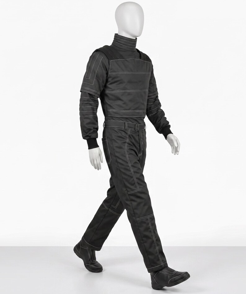 Pu&ograve; includere: Tuta nera con dettagli di cuciture bianche, esposta su un manichino. L'outfit presenta un collo alto, maniche lunghe e una cintura. I pantaloni hanno un design a gamba dritta e il manichino indossa stivali neri.