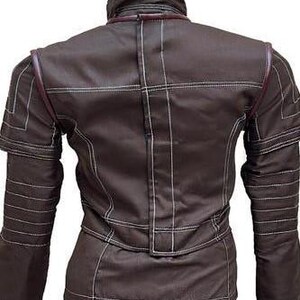 May include: A dark brown jacket featuring a high collar and long sleeves with ribbed detailing. The garment is constructed with prominent white contrast stitching throughout, including horizontal and vertical lines, and dark brown piping accents.