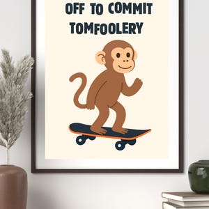 Peut inclure: Impression encadrée avec un singe marron sur un skateboard. Le texte "OFF TO COMMIT TOMFOOLERY" est au-dessus du singe en bleu foncé. Le singe sourit. Le fond est beige clair.