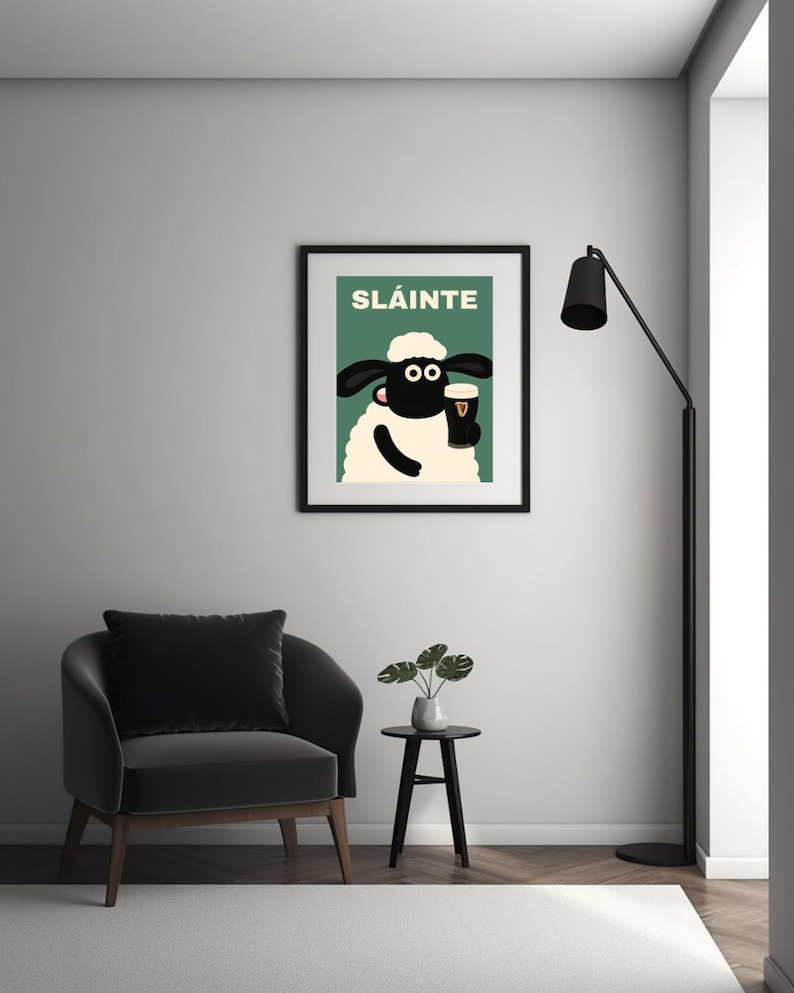 May include: A framed art print featuring a cartoon sheep holding a pint of stout. The print has the word "SL&Aacute;INTE" in green letters at the top. The sheep is black and white with a white fluffy body and a black frame.