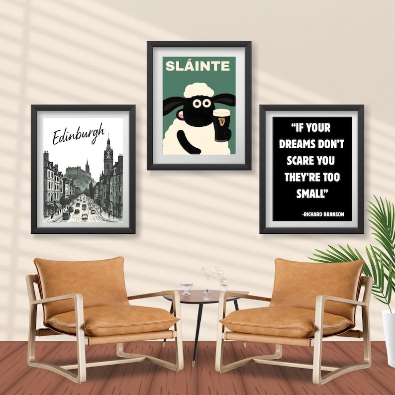 May include: Three framed art prints hang on a wall above two leather armchairs. The prints include a cityscape of Edinburgh, a cartoon sheep with a pint, and a quote by Richard Branson. The chairs have wooden frames and a small table.