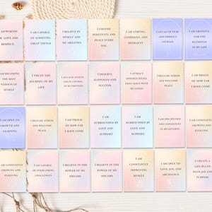 May include: A collection of affirmation cards with pastel backgrounds and inspirational phrases. Each card features a different positive statement, such as "I am worthy of love and respect." The cards are arranged on a neutral surface.