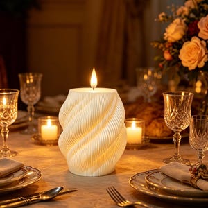 May include: A lit, white, spiral-patterned candle on a dining table. The candle's warm glow illuminates crystal glasses, plates, and cutlery. A floral arrangement is in the background, creating a warm, inviting atmosphere.
