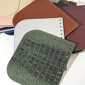 May include: A collection of leather bag bases in various colors, including beige, brown, white, and green. The bases have pre-punched holes for stitching and feature different textures, such as a crocodile pattern.