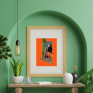 May include: A framed art print with a collage on an orange background. The collage includes a person wearing sunglasses, a black top, and yellow trousers. The frame is gold, and the wall is green.