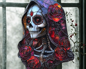 Könnte beinhalten: Buntglas-Totenkopf zum Tag der Toten mit Kapuze und roten Rosen. Der Schädel hat rote Edelstein-Akzente. Das Stück hängt vor einem Fenster.