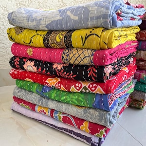 Pu&ograve; includere: Una pila di trapunte colorate e piegate. Le trapunte mostrano una variet&agrave; di motivi e colori, tra cui giallo, rosa, rosso, verde e blu. Ogni trapunta &egrave; fatta di tessuto e ha un design cucito.