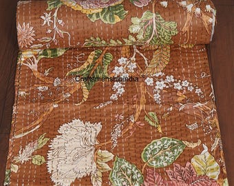 May include: Rolled brown quilt with a floral pattern in white, green, and pink. The quilt features a repeating design of large flowers and leaves, with the text "Craftsmanshipindia" visible. The quilt is stitched with white thread.