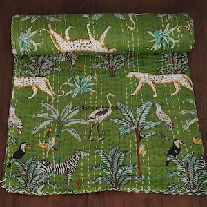 Op de afbeelding: Groene quilt met een jungle-ontwerp, met luipaarden, zebra's, toekans en andere dieren. De quilt is met de hand gestikt met witte draad en heeft een opgerold gedeelte aan de bovenkant. Het ontwerp omvat palmbomen en tropische planten.