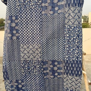 Może przedstawiać: Niebiesko-biała patchworkowa kołdra z różnymi geometrycznymi i kwiatowymi wzorami. Kołdra zawiera mieszankę kropek, spiral i wzorów w kształcie liści. Paleta kolorów to głównie indygo i biel.