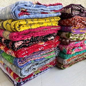 Pu&ograve; includere: Pile di trapunte colorate e piegate. Le trapunte mostrano una variet&agrave; di motivi e colori, tra cui blu, giallo, rosa, rosso, verde e viola. Le trapunte sembrano fatte a mano e hanno un design cucito.