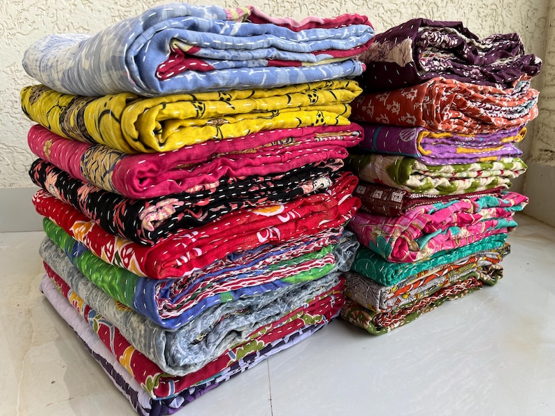 Pu&ograve; includere: Pile di trapunte colorate e piegate. Le trapunte mostrano una variet&agrave; di motivi e colori, tra cui blu, giallo, rosa, rosso, verde e viola. Le trapunte sembrano fatte a mano e hanno un design cucito.