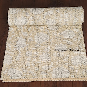 Può includere: Trapunta a motivi floreali beige e bianca, arrotolata. La trapunta presenta un design dettagliato di fiori e foglie, cucito con filo scuro. Il testo "craftsmanshipindia" è visibile sulla trapunta.