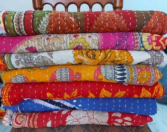 May include: A stack of colorful, patterned quilts. The quilts feature various designs, including floral and geometric patterns, in shades of red, pink, yellow, green, and blue. Each quilt is folded and stacked on top of each other.