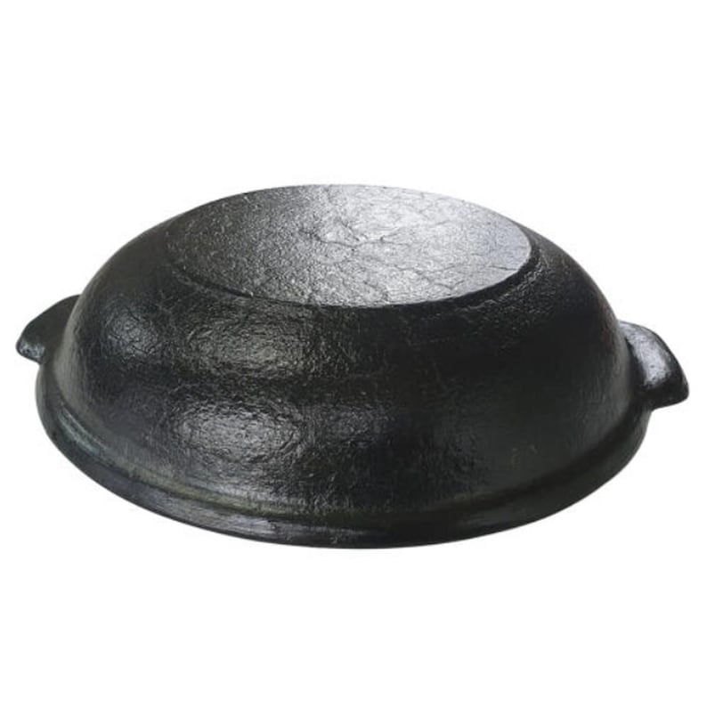May include: A black cast iron pot with a rounded shape and two small handles on the sides. The pot has a textured surface and a flat bottom. This cookware is suitable for various cooking methods.