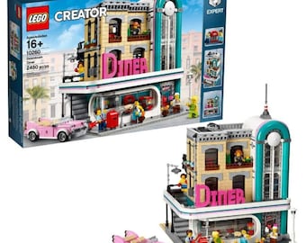 May include: A LEGO Creator Expert Downtown Diner set. The building is tan and teal with a pink "Diner" sign. A pink classic car is parked in front. The set includes mini-figures and accessories. The box reads "16+" and "2480 pcs".