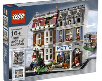 May include: A LEGO set box featuring a detailed building facade with a pet shop. The building has multiple stories, with windows, balconies, and a red and gray roof. The box reads "LEGO" and "PETS" with the age range "16+". The set includes 2032 pieces.