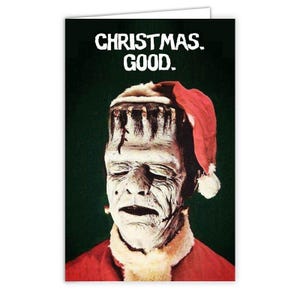 Könnte beinhalten: Weihnachtskarte mit dem Text "CHRISTMAS. GOOD." auf dunkelgrünem Hintergrund. Sie zeigt Frankenstein mit Weihnachtsmütze und rotem Mantel. Das Gesicht des Monsters ist blass mit dunklen Linien und einem traurigen Ausdruck.