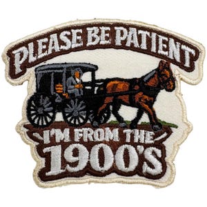 Könnte beinhalten: Gestickter Aufnäher mit dem Text "PLEASE BE PATIENT I'M FROM THE 1900'S". Der Aufnäher zeigt eine Pferdekutsche mit einem Fahrer. Der Text und das Bild sind in Braun-, Schwarz- und Beigetönen gehalten.
