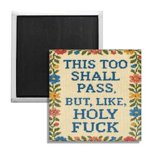 May include: A square magnet with a white border and a black magnetic surface. The magnet features a cross-stitch design with the text "THIS TOO SHALL PASS, BUT, LIKE, HOLY FUCK" in blue, surrounded by a floral border.