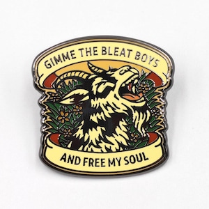Könnte beinhalten: Rechteckiger Emaille-Pin mit einem schwarzen Ziegenkopf, offenem Mund und Hörnern. Der Pin hat ein gelbes Banner oben mit dem Text "GIMME THE BLEAT BOYS" und ein Banner unten mit dem Text "AND FREE MY SOUL". Die Ziege ist von grünen Blättern und Blumen umgeben.