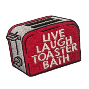 Könnte beinhalten: Ein rot-grauer, gestickter Aufnäher in Form eines Toasters. Der Aufnäher zeigt die Worte "LIVE LAUGH TOASTER BATH" in weißer Schrift. Der Toaster hat schwarze Schlitze und einen silbernen Hebel.