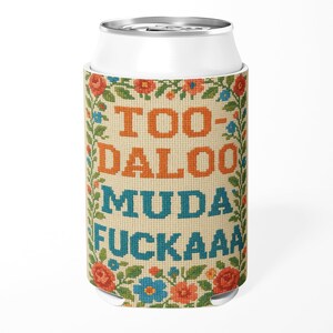 May include: A white drinks can cooler with a cross-stitch design. The design features the words "TOO-DALOO MUDA FUCKAAA" in orange and blue, framed by a floral border with red, blue, and orange flowers.