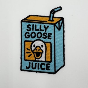 Può includere: Toppa ricamata con un design a forma di cartone di succo con la scritta "SILLY GOOSE JUICE". La toppa ha uno sfondo azzurro, una parte superiore gialla e una cannuccia. Il cartone del succo presenta una faccia di oca dei cartoni animati.