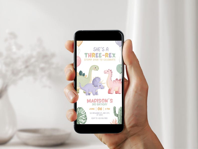 May include: A smartphone displays a colorful birthday invitation with dinosaur illustrations. The text reads "She's a Three-Rex" and includes details for a 3rd birthday celebration. The design features pastel colors and cartoon dinosaurs.