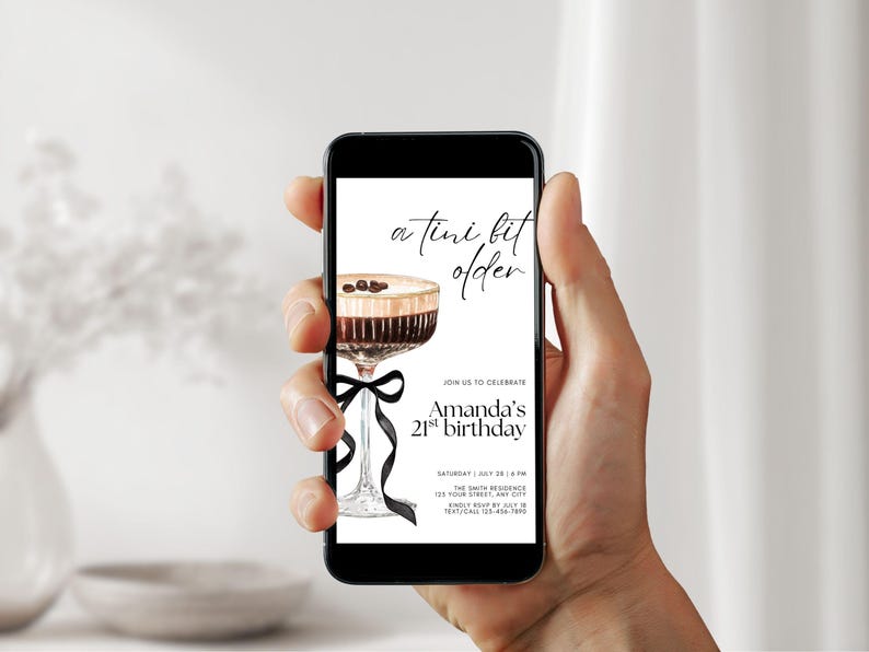 May include: A smartphone displays a birthday invitation with a watercolor illustration of a cocktail. The invitation text reads "a tini bit older" and "Amanda's 21st birthday". A black ribbon adorns the cocktail glass.